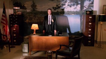 Movie still from “Twin Peaks: Fire Walk with Me” (1992), directed by David Lynch – A man standing in front of a wooden desk; Wide shot, Low angle