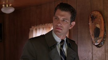 Movie still from “Twin Peaks: Fire Walk with Me” (1992), directed by David Lynch – A man wearing a suit and tie standing in front of a wooden wall; Close Up shot, Low angle
