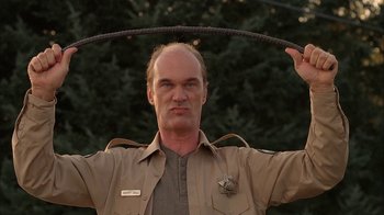 Movie still from “Twin Peaks: Fire Walk with Me” (1992), directed by David Lynch – A man holding a rope in front of a tree; Close Up shot, Low angle