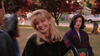 Movie still from “Twin Peaks: Fire Walk with Me” (1992), directed by David Lynch – A woman with blonde hair smiles for the camera; Medium shot, Over the shoulder angle