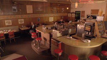 Movie still from “Twin Peaks: Fire Walk with Me” (1992), directed by David Lynch – People sitting at a restaurant with red stools; Wide shot, High angle