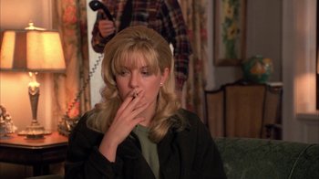Movie still from “Twin Peaks: Fire Walk with Me” (1992), directed by David Lynch – A woman smoking a cigarette while sitting on a couch; Close Up shot, High angle