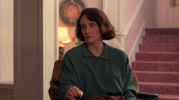 Movie still from “Twin Peaks: Fire Walk with Me” (1992), directed by David Lynch – A woman sitting in a chair holding a remote control; Medium shot, Over the shoulder angle