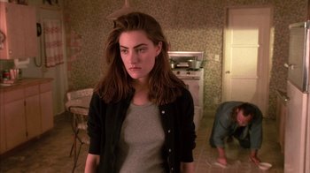 Movie still from “Twin Peaks: Fire Walk with Me” (1992), directed by David Lynch – A woman standing in a room with a man standing in the background; Medium shot, High angle