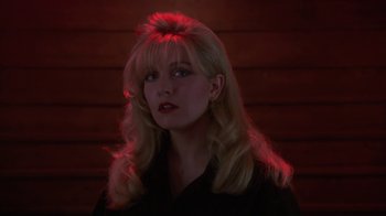 Movie still from “Twin Peaks: Fire Walk with Me” (1992), directed by David Lynch – A woman with blonde hair and red lighting in a dark room; Close Up shot, Low angle