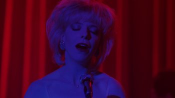 A woman singing into a microphone in a red room
