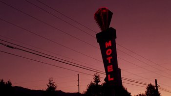 Movie still from “Twin Peaks: Fire Walk with Me” (1992), directed by David Lynch – A motel sign lit up at night in the dark; Extreme Wide shot, Low angle