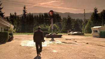Movie still from “Twin Peaks: Fire Walk with Me” (1992), directed by David Lynch – A man is walking down the street near a stop sign; Extreme Wide shot, Low angle