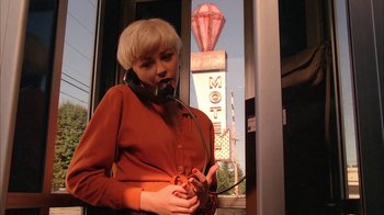 A woman in a red shirt is holding a cell phone