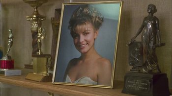 Movie still from “Twin Peaks: Fire Walk with Me” (1992), directed by David Lynch – A picture of a woman in a white dress is sitting on top of a table; Close Up shot, Low angle