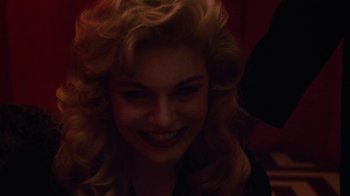 Movie still from “Twin Peaks: Fire Walk with Me” (1992), directed by David Lynch – A person with curly hair smiling; Close Up shot, Over the shoulder angle