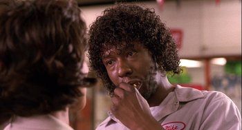 Movie still from “Two Can Play That Game” (2001), directed by Mark Brown – A man with curly black hair is eating a donut; Close Up shot, Low angle