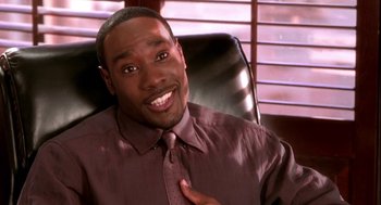 Movie still from “Two Can Play That Game” (2001), directed by Mark Brown – A man sitting in an office chair wearing a purple shirt; Close Up shot, High angle