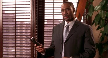 Movie still from “Two Can Play That Game” (2001), directed by Mark Brown – A man in a business suit holding a cell phone; Close Up shot, Low angle