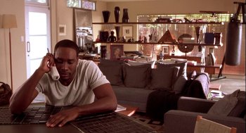 Movie still from “Two Can Play That Game” (2001), directed by Mark Brown – A man sitting at a table in front of a computer; Medium shot, High angle