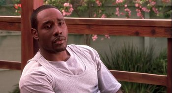 Movie still from “Two Can Play That Game” (2001), directed by Mark Brown – A man sitting on a bench in front of flowers; Close Up shot, High angle