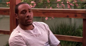 Movie still from “Two Can Play That Game” (2001), directed by Mark Brown – A man sitting on top of a wooden bench in front of flowers; Close Up shot, High angle