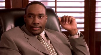 Movie still from “Two Can Play That Game” (2001), directed by Mark Brown – A man in a suit and tie sitting in a chair; Close Up shot, Low angle