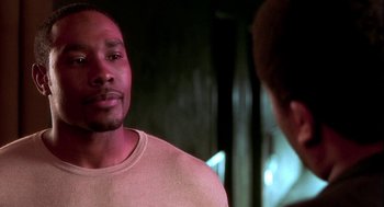 Movie still from “Two Can Play That Game” (2001), directed by Mark Brown – A man standing next to another man in front of a window; Close Up shot, Over the shoulder angle