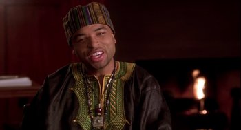 Movie still from “Two Can Play That Game” (2001), directed by Mark Brown – A man wearing a colorful hat and a black and green outfit; Close Up shot, Over the shoulder angle