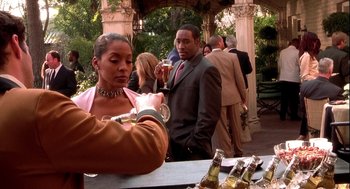 Movie still from “Two Can Play That Game” (2001), directed by Mark Brown – A man and a woman are standing at an outdoor party; Medium shot, Over the shoulder angle