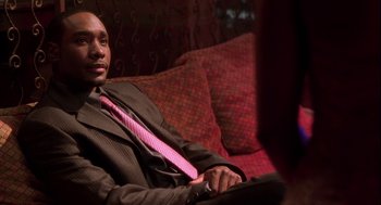 Movie still from “Two Can Play That Game” (2001), directed by Mark Brown – A man sitting on a couch wearing a suit and a pink neck tie; Close Up shot, High angle