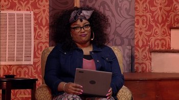 Movie still from “Madea on the Run” (2017), directed by Derrick Doose – A woman sitting in a chair holding a laptop; Medium shot, Over the shoulder angle