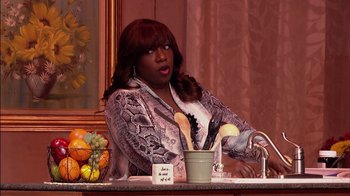 Movie still from “Madea on the Run” (2017), directed by Derrick Doose – A woman sitting at a sink with a spoon in her hand; Medium shot, Over the shoulder angle