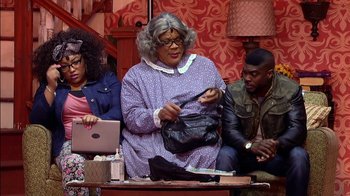 Movie still from “Madea on the Run” (2017), directed by Derrick Doose – A group of people sitting around a table with a purse; Medium shot, High angle