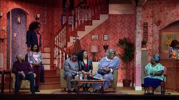 Movie still from “Madea on the Run” (2017), directed by Derrick Doose – A group of people sitting in a living room on a stage; Wide shot, High angle