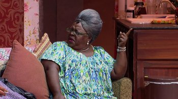 Movie still from “Madea on the Run” (2017), directed by Derrick Doose – An older woman sitting in a chair with her finger up to her ear; Medium shot, Over the shoulder angle