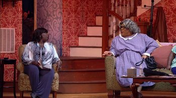 Movie still from “Madea on the Run” (2017), directed by Derrick Doose – Two women are sitting on a chair in front of each other; Medium shot, Over the shoulder angle
