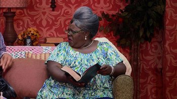 Movie still from “Madea on the Run” (2017), directed by Derrick Doose – An older woman sitting on a couch reading a book; Medium shot, Over the shoulder angle