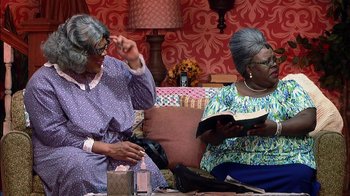 Movie still from “Madea on the Run” (2017), directed by Derrick Doose – Two older women sitting on a couch reading a book; Medium shot, High angle