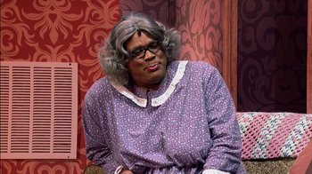 Movie still from “Madea on the Run” (2017), directed by Derrick Doose – A woman in a purple dress sitting on a couch; Medium shot, Over the shoulder angle