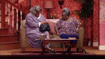 Movie still from “Madea on the Run” (2017), directed by Derrick Doose – Two older women sitting on a couch and one of the women is holding a purse; Wide shot, High angle