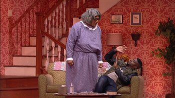 Movie still from “Madea on the Run” (2017), directed by Derrick Doose – A man and a woman are sitting on a couch in a living room; Medium shot, High angle