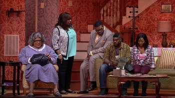 Movie still from “Madea on the Run” (2017), directed by Derrick Doose – A group of people sitting on couches in a living room; Wide shot, Over the shoulder angle
