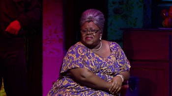 Movie still from “Madea on the Run” (2017), directed by Derrick Doose – An older woman sitting on a chair wearing a purple dress; Medium shot, Over the shoulder angle