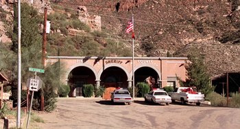 Movie still from “U Turn” (1997), directed by Oliver Stone – A group of cars parked in front of a building; Extreme Wide shot, High angle