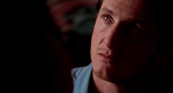 Movie still from “U Turn” (1997), directed by Oliver Stone – A man's face in a dark room; Close Up shot, Over the shoulder angle