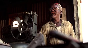 Movie still from “U Turn” (1997), directed by Oliver Stone – An older man wearing glasses and a head scarf; Close Up shot, Low angle