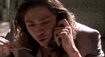 Movie still from “U Turn” (1997), directed by Oliver Stone – A person talking on a cell phone; Close Up shot, Low angle