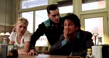 Movie still from “U Turn” (1997), directed by Oliver Stone – Two men and a woman sitting at a wooden table; Medium shot, Low angle