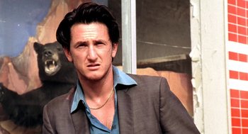 Movie still from “U Turn” (1997), directed by Oliver Stone – A person wearing a suit and a necklace; Close Up shot, Low angle