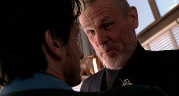 Movie still from “U Turn” (1997), directed by Oliver Stone – A man in a suit and tie looking at another man in a suit and tie; Close Up shot, Low angle