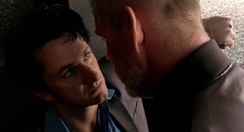 Movie still from “U Turn” (1997), directed by Oliver Stone – A man in a suit and tie talking to another man in a suit and tie; Close Up shot, Over the shoulder angle
