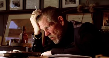 Movie still from “U Turn” (1997), directed by Oliver Stone – An older man sitting at a table with a cigarette in his mouth; Close Up shot, Low angle