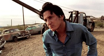 Movie still from “U Turn” (1997), directed by Oliver Stone – A man in a blue dress shirt is looking at the camera; Close Up shot, Low angle