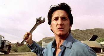 Movie still from “U Turn” (1997), directed by Oliver Stone – A man holding a wrench in his hand; Close Up shot, Low angle